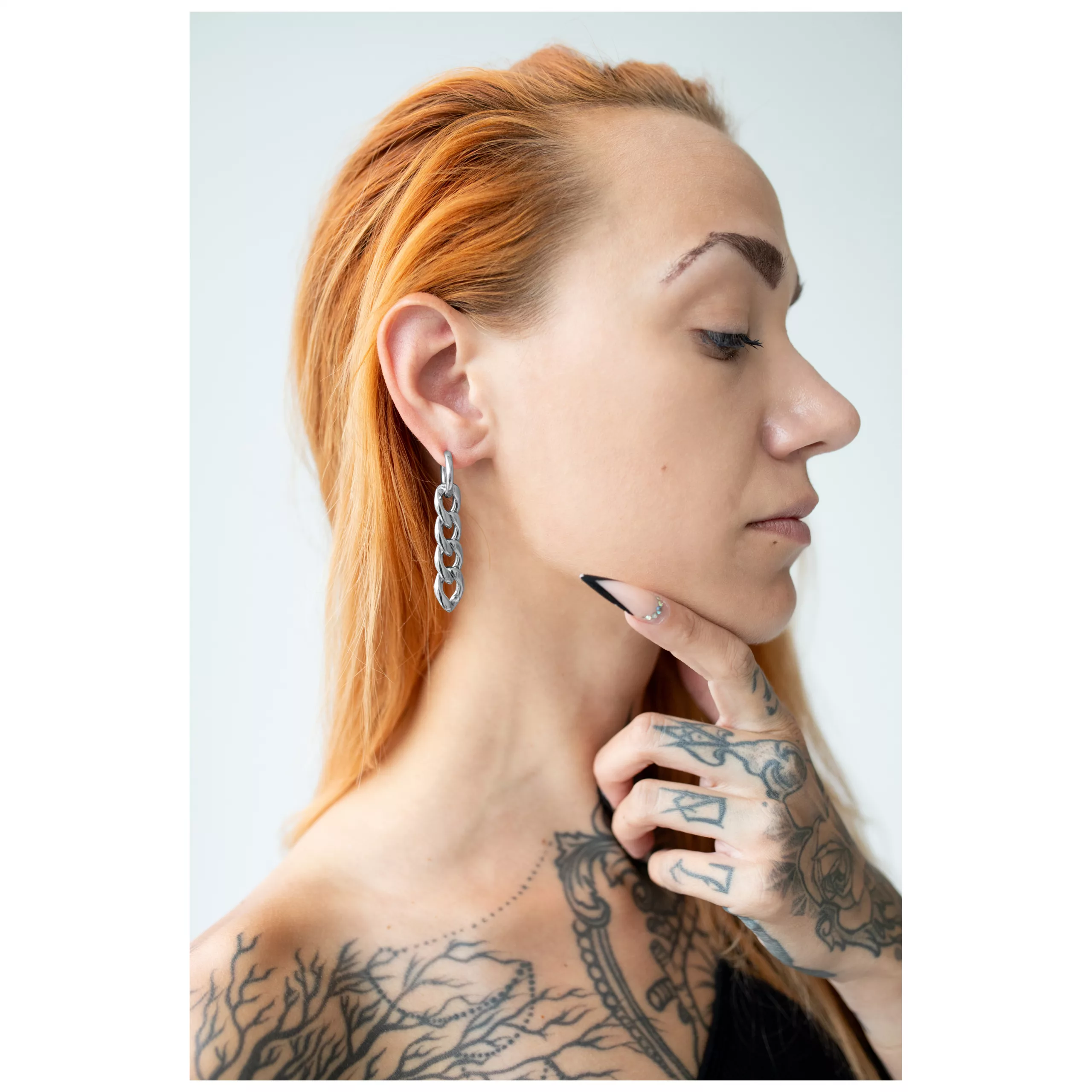 Silberne Little Chunky Hoops am Ohr Silberne Ohrringe im Kettendesign getragen an einem Ohr mit tätowierter Hand und rotem Haar