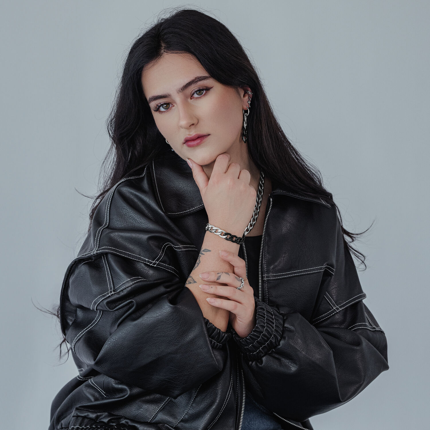 Person trägt ein massives Armband in Silber und Schwarz auf neutralem Hintergrund