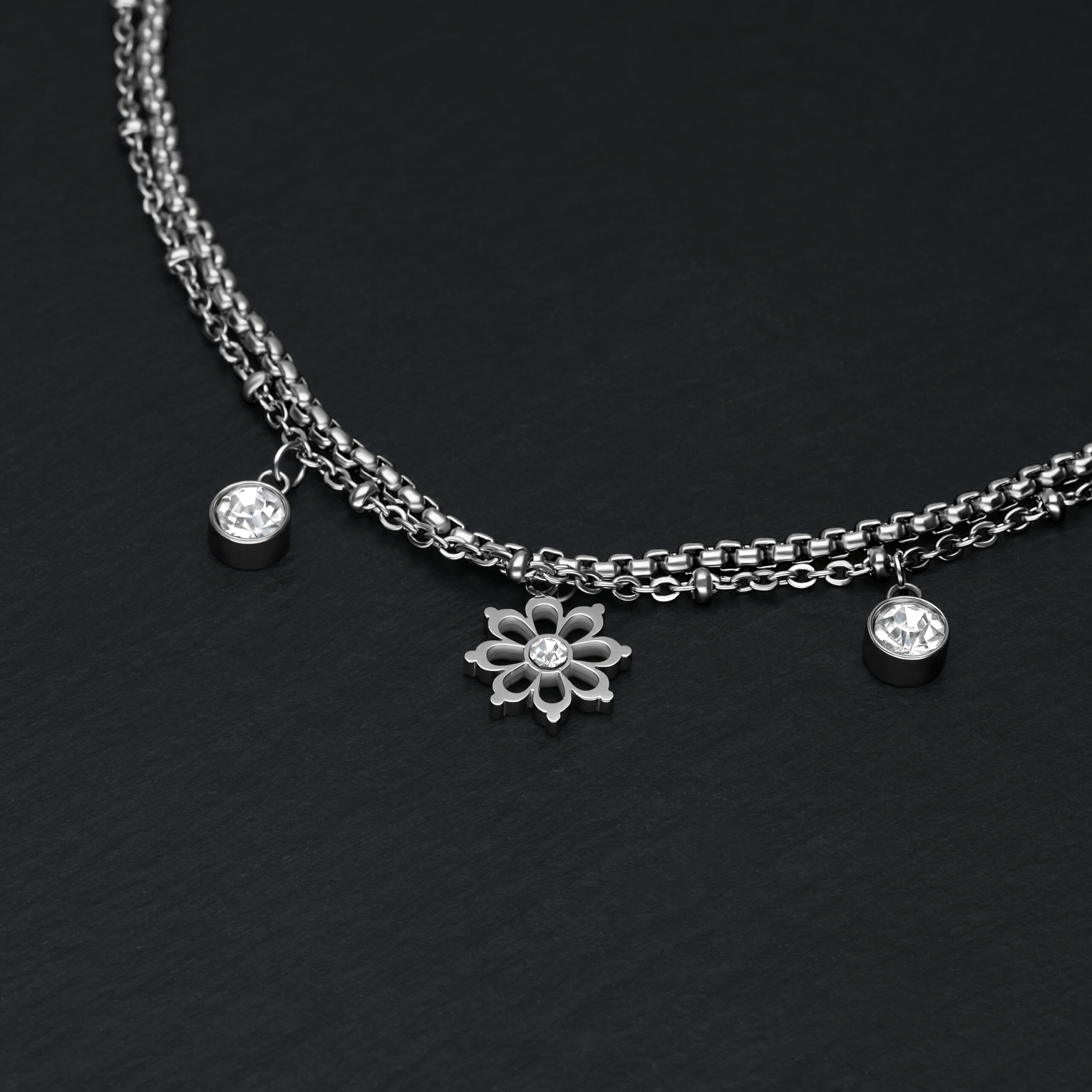 Silbernes Armband auf schwarzem Hintergrund mit floralen Anhängern und Kristallen