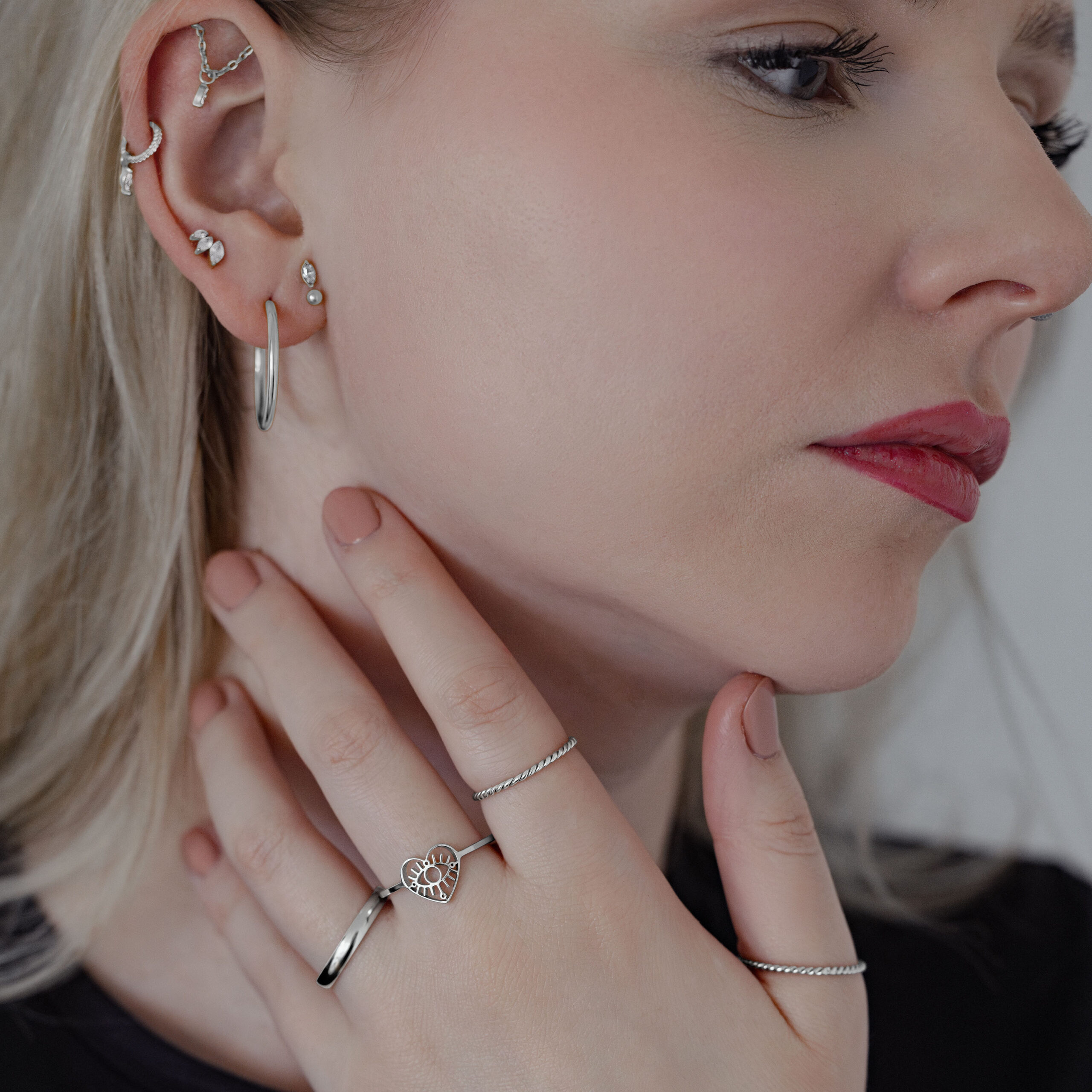 Frau mit mehreren Ohrringen, die einen silbernen Twisted Ring trägt