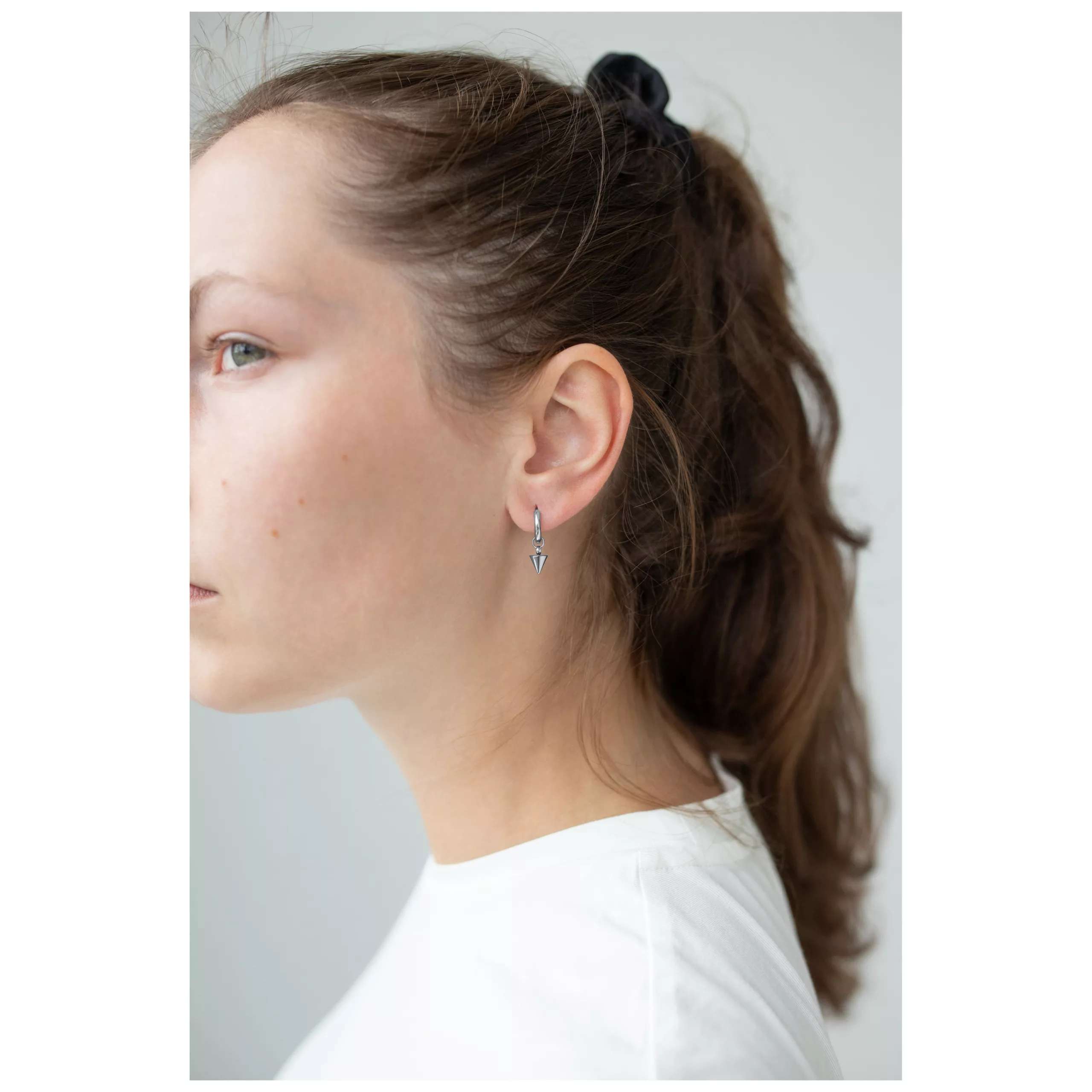 Kleine Spike Creolen aus Chirurgenstahl Frau trägt kleine schwarze Spike Creolen an ihrem Ohr, weißer Hintergrund