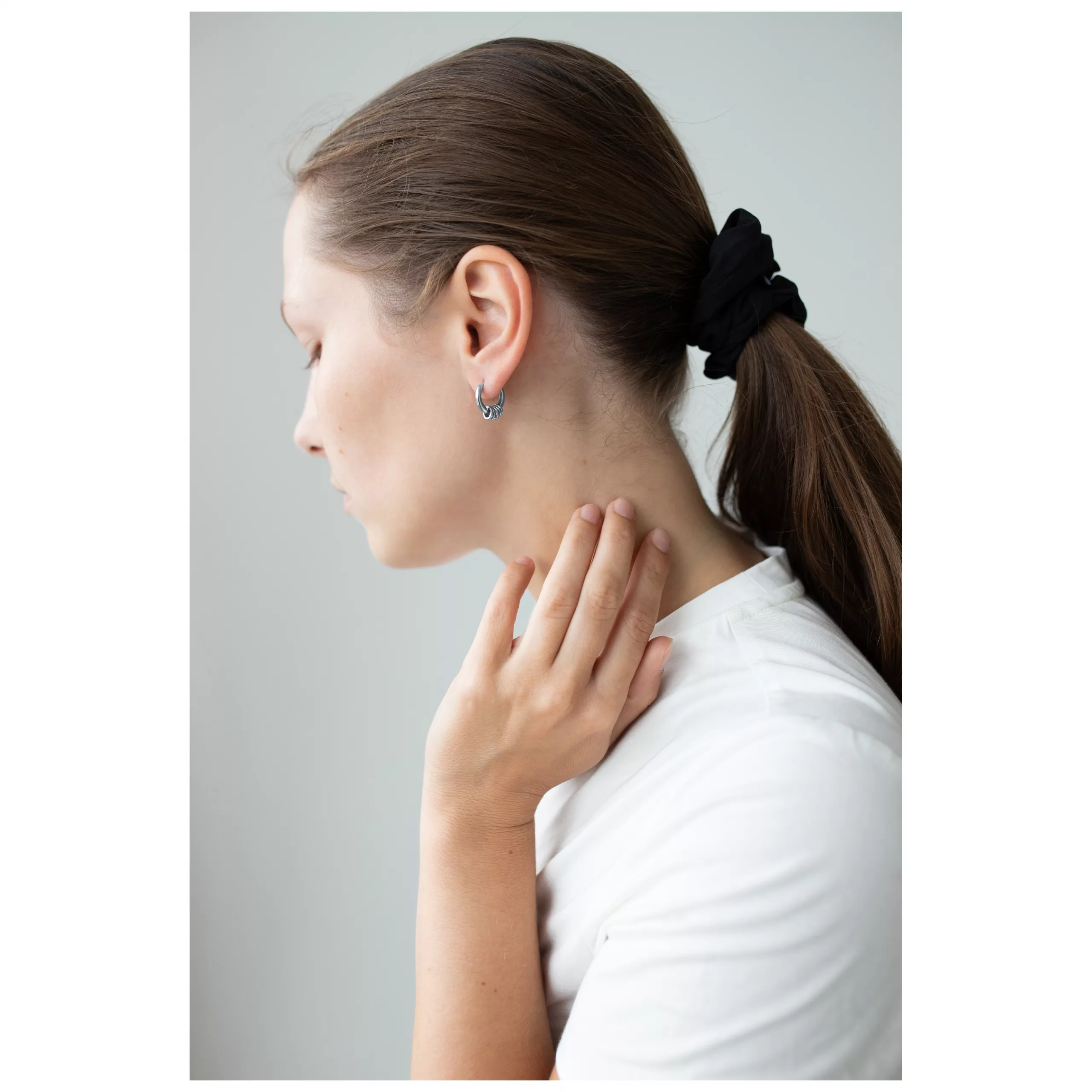 Elegante Little 5 Rings Hoops in Schwarz Frau mit schwarzen Little 5 Rings Hoops Ohrringen und Pferdeschwanz