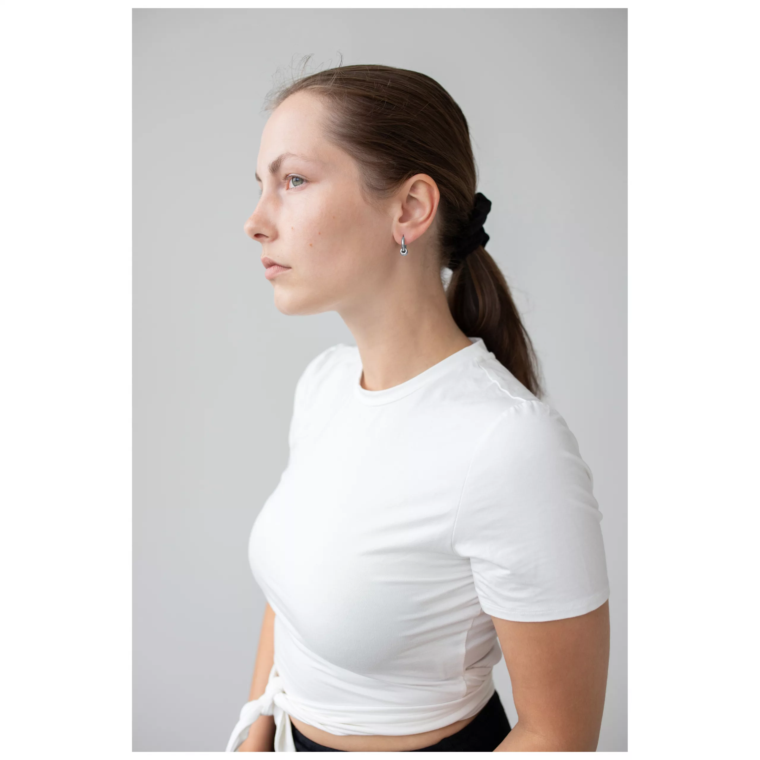 Elegante Little 5 Rings Hoops Ohrringe Frau mit Little 5 Rings Hoops Ohrringen in Schwarz und Silber vor grauem Hintergrund