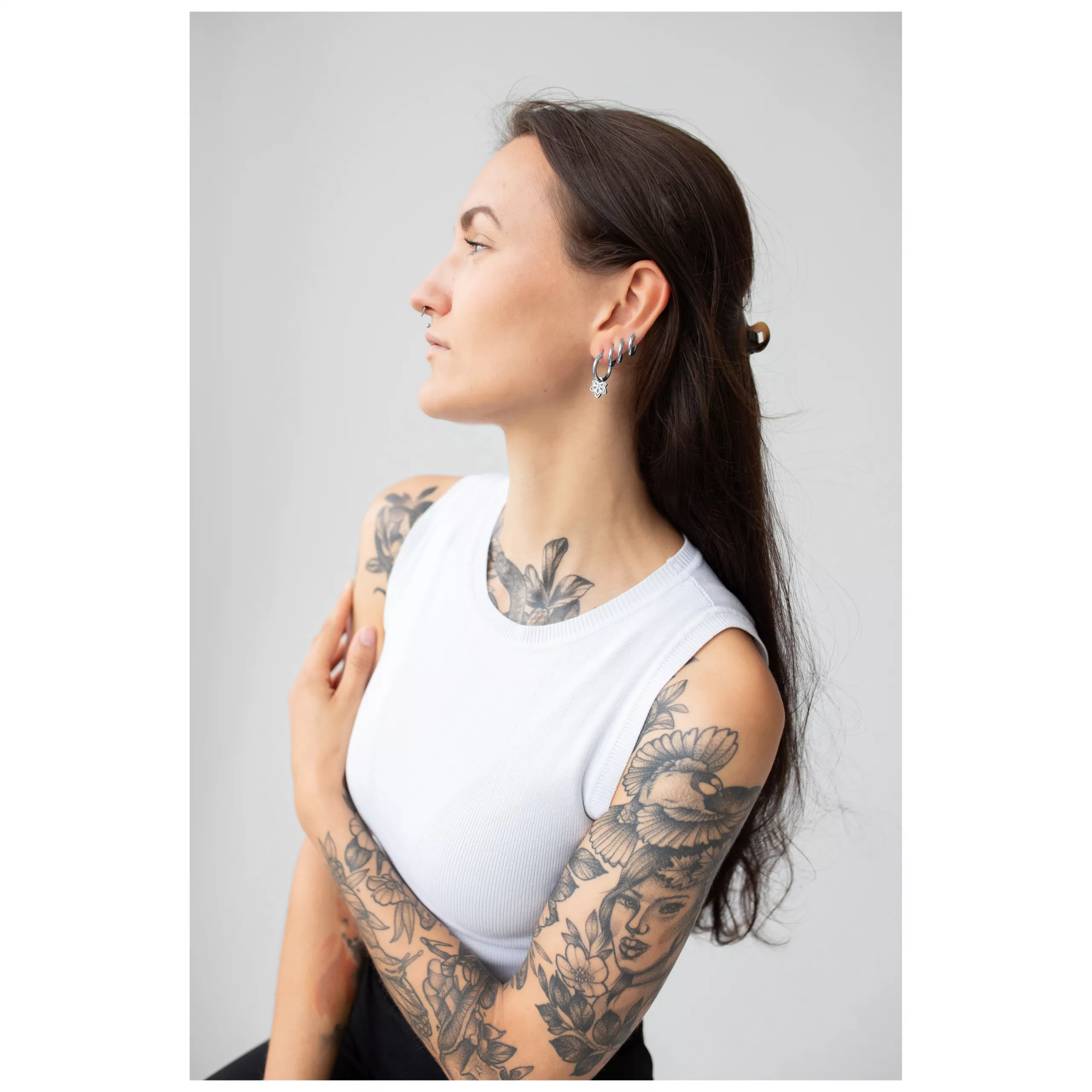 Frau mit langen Haaren trägt stilvolle Little Flower Hoops Ohrringe auf grauem Hintergrund