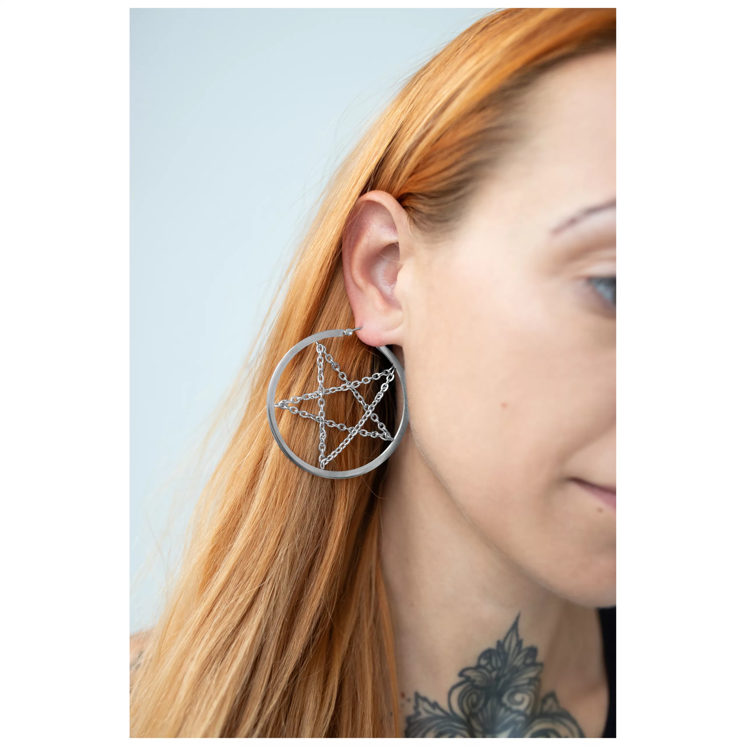 Silberne Pentagram Ohrringe mit Kette, getragen am Ohr, helle Hintergrund