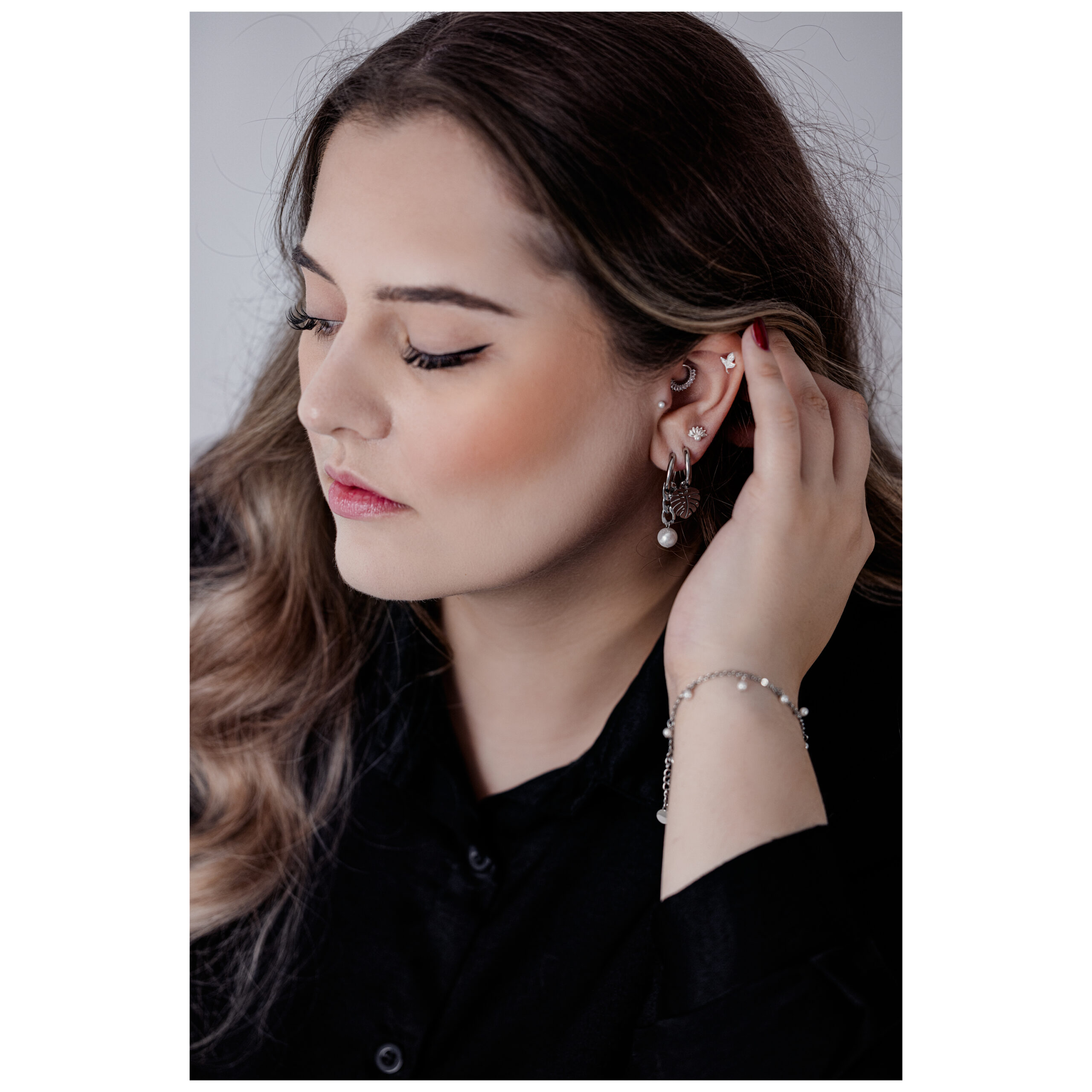 Elegantes Little Pearl Armband in Schwarz und Silber Frau mit langem Haar trägt ein schwarzes und silbernes Armband und Ohrringe