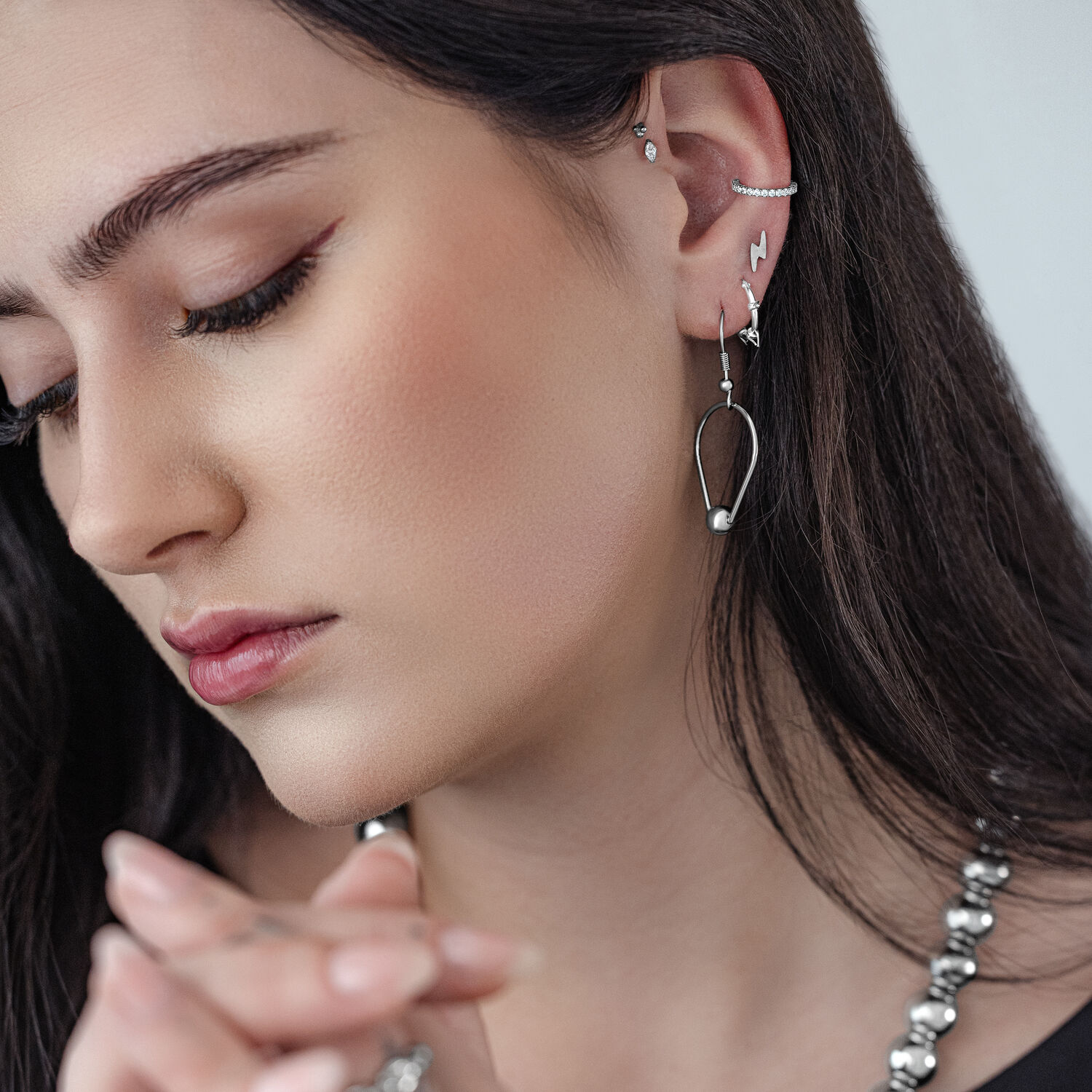 Teardrop-Ring Ohrringe aus Chirurgenstahl Frau mit silbernen Teardrop-Ring Ohrringen vor grauem Hintergrund