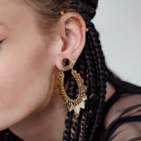 Frau mit goldenen Sonnenblumen-Ohrringen und geflochtenem Haar