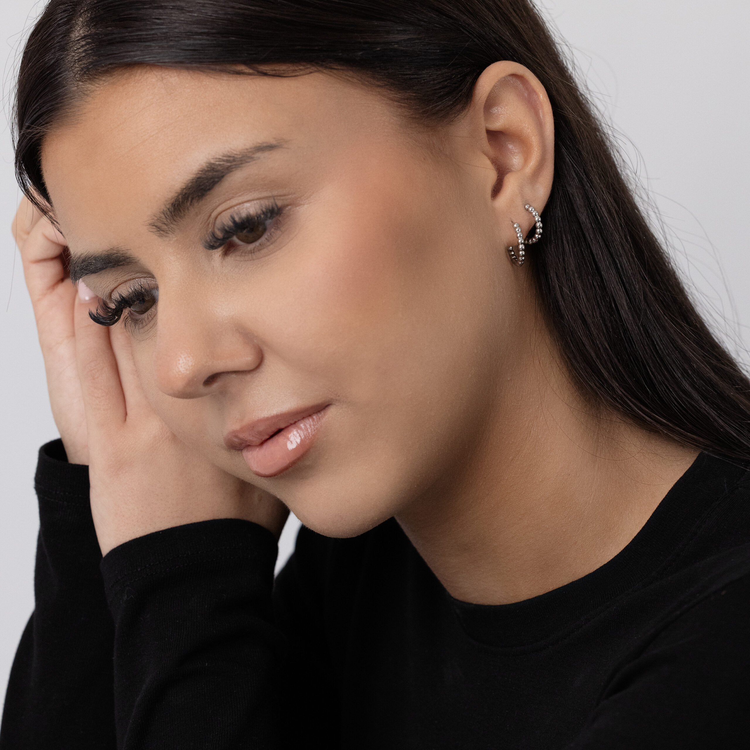 Frau mit schwarzen Bubble Hoops Ohrringen aus Edelstahl auf hellem Hintergrund