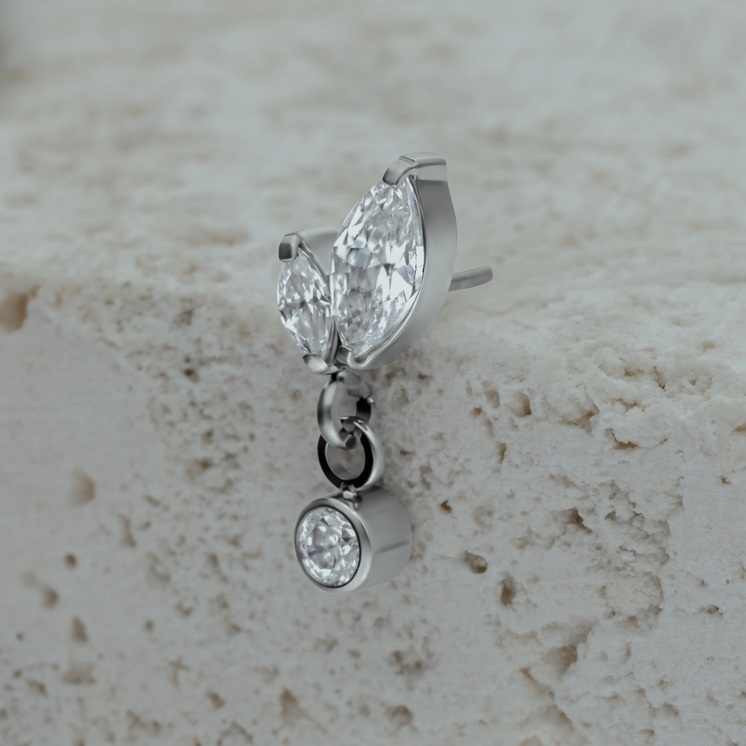 Silberner Piercing Aufsatz mit zwei marquiseförmigen Kristallen und einem hängenden Kristall auf Stein