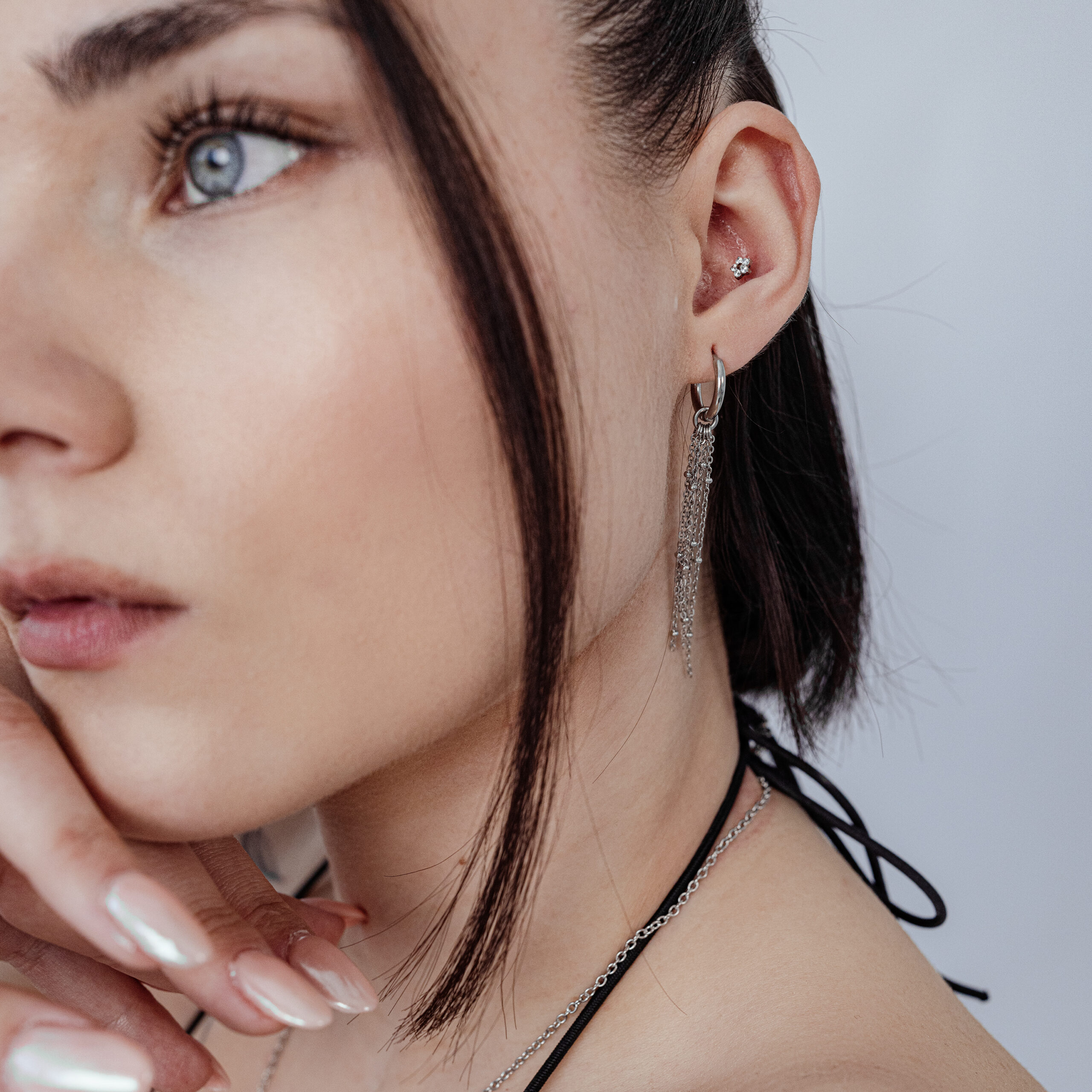 Frau mit Push Fit Blumenaufsatz im Ohr, silberne Kette und Ohrringe, weißer Hintergrund