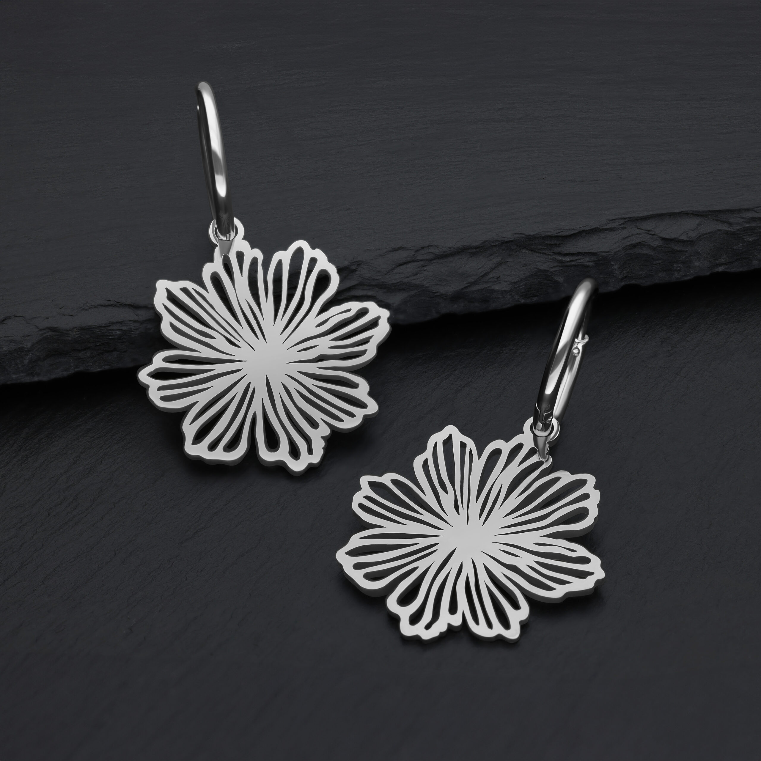 Silberne Edelstahl-Ohrringe mit Blumendesign auf dunklem Hintergrund