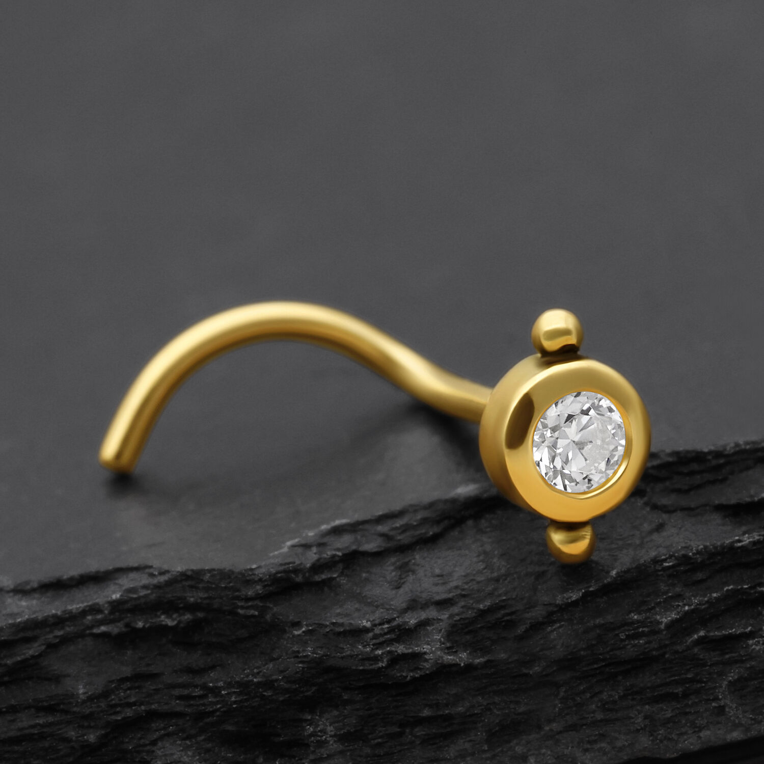 Goldener Nasenstecker mit klarem Kristall auf dunklem Hintergrund