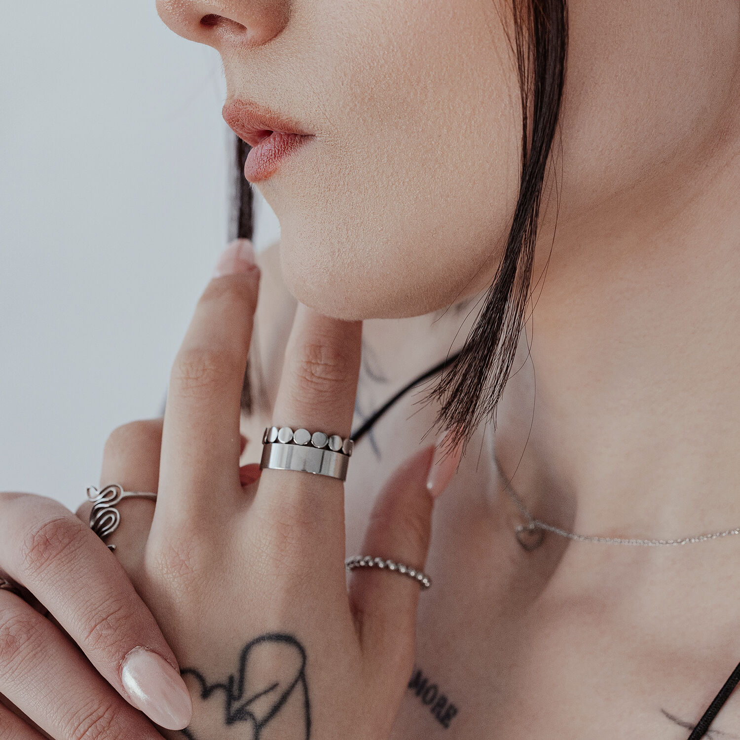 Nahaufnahme eines unisex Feinplattenrings am Finger, Silber, Haut mit Tätowierungen im Hintergrund