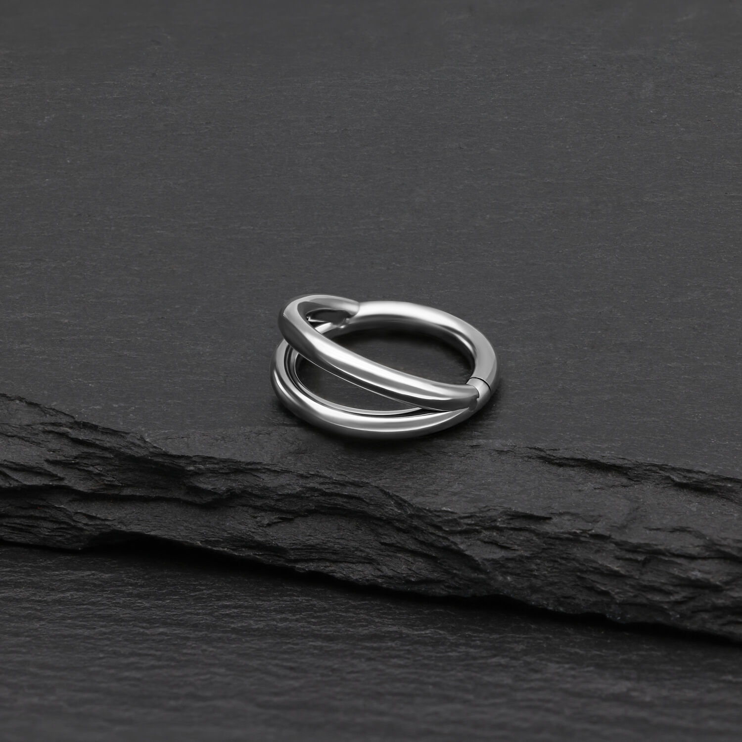 Silberner doppelreihiger Clicker Ring aus Titan auf schwarzem Hintergrund