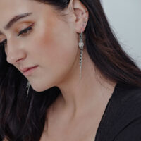 Bubble Heart Hoops mit Perle, getragen am Ohr Frau mit langen, dunklen Haaren trägt silberne Bubble Heart Hoops mit Perle in ihrem Ohr