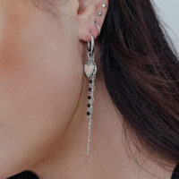 Silberne Herz-Ohrringe mit Perle und Ketten Silberne Herz-Ohrringe mit Perlenanhänger und Ketten, getragen am Ohr