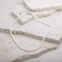 Synthetische Perlenkette aus Chirurgenstahl auf hellem Stein