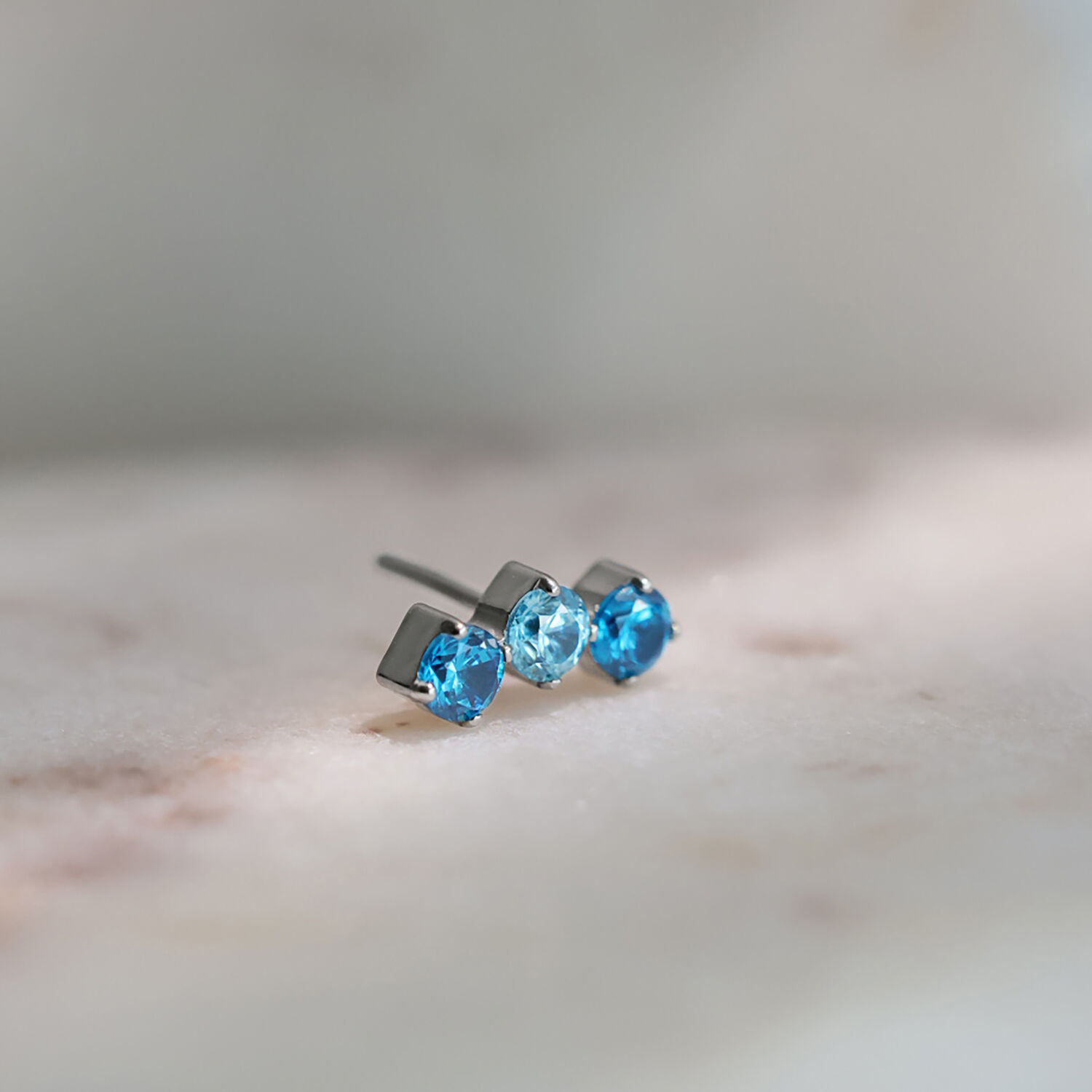 Silberner Titanaufsatz mit drei Kristallen in Lavendel und Türkis auf hellem Hintergrund