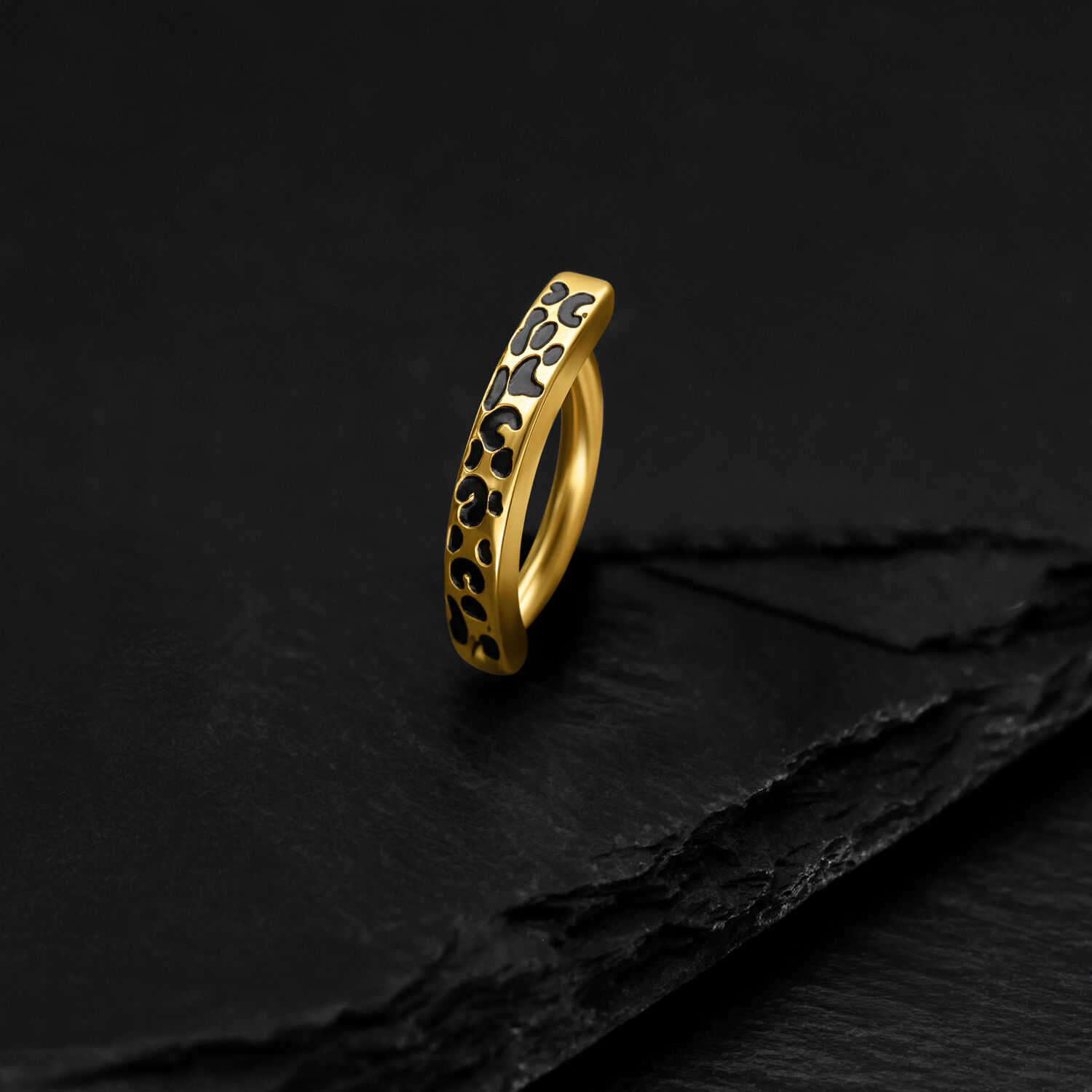 Goldener Bauchnabel Clicker mit Leopardenmuster auf schwarzem Hintergrund