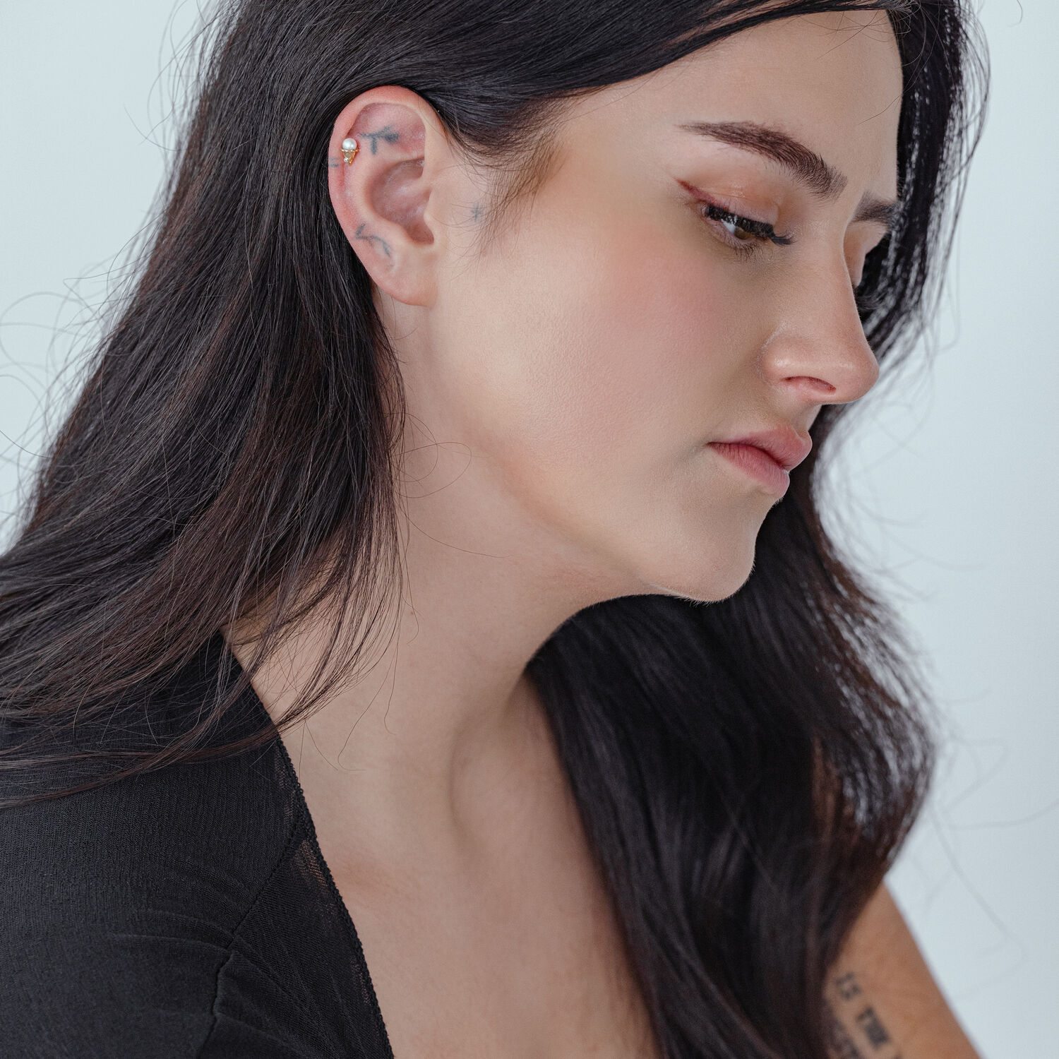 Frau mit goldenem Titan Push Fit Aufsatz im Ohr, seitlich auf weißem Hintergrund