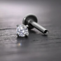 Silberner Prong Aufsatz mit Kristall für Innengewinde Labret auf grauem Hintergrund