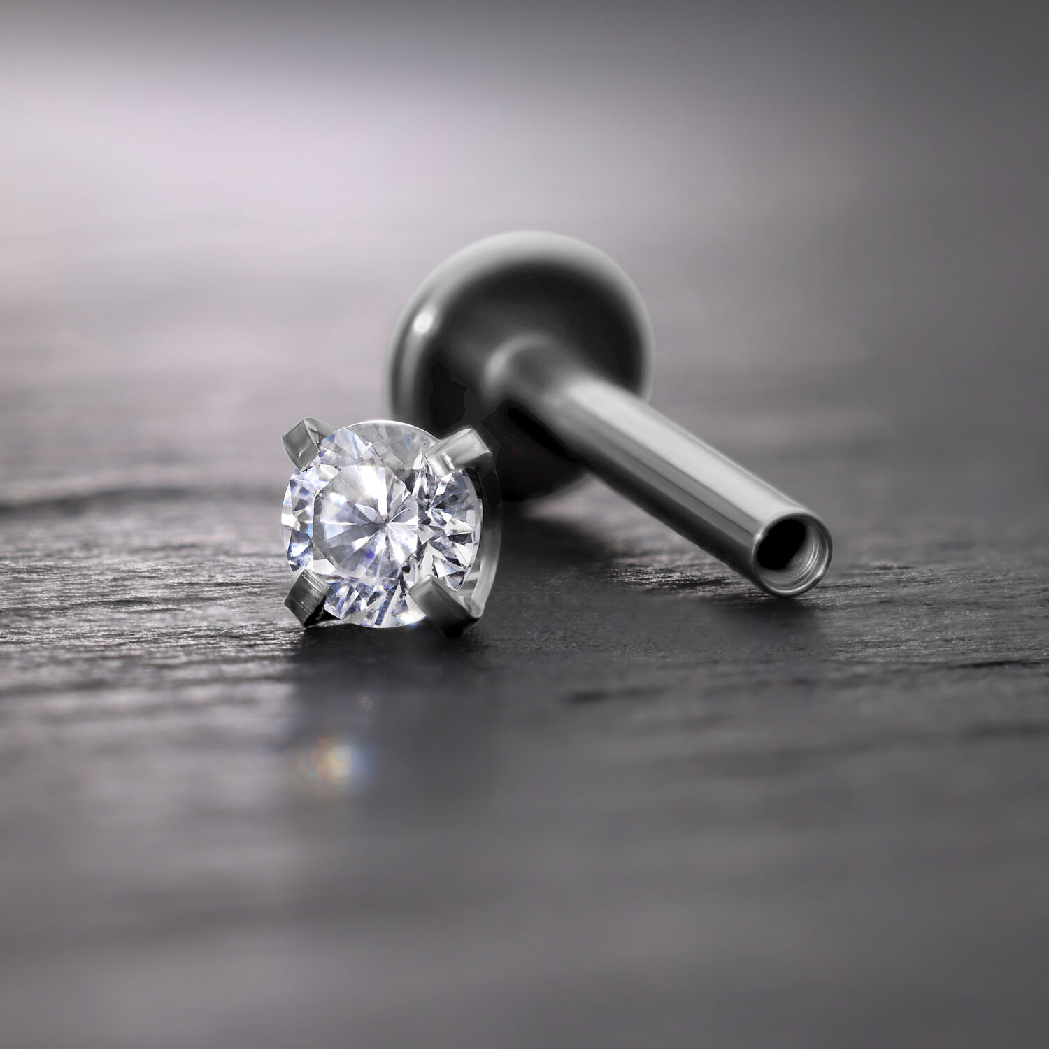 Silberner Prong Aufsatz mit Kristall für Innengewinde Labret auf grauem Hintergrund