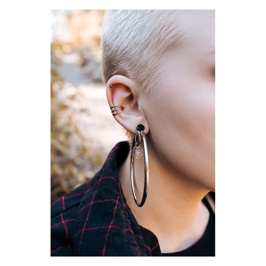 Person mit 3er Clicker Ring in Schwarz und Silber im Ohr, Naturhintergrund