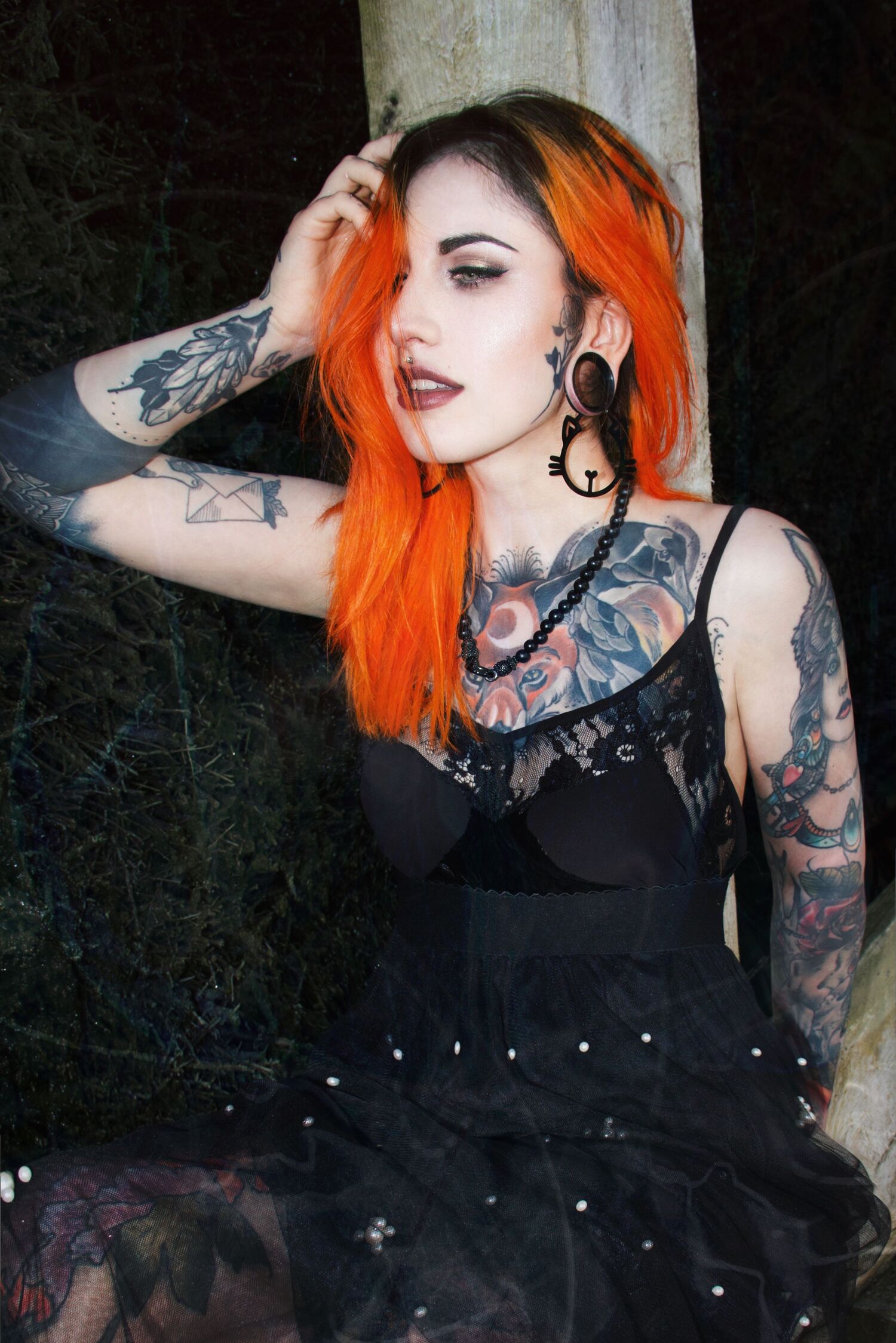 Frau mit orangefarbenem Haar und schwarzen Meow Hoops Ohrringen im Wald