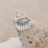 Silberner Piercing-Ring mit klaren Kristallen auf beigem Hintergrund