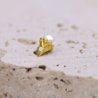 Goldener Push Fit Aufsatz mit klarem Kristall auf hellem Stein