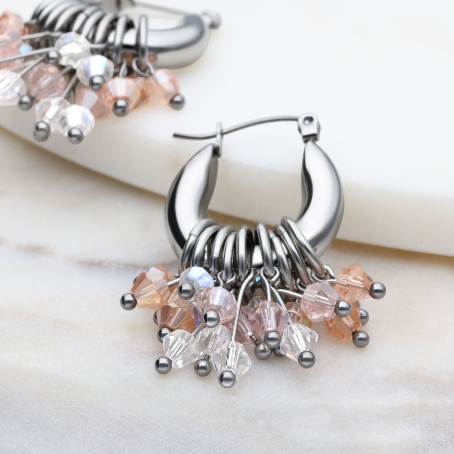 Glamour Hoops Ohrringe in Silber mit Kristallen Silberne Glamour Hoops Ohrringe mit bunten Kristallen auf marmoriertem Hintergrund