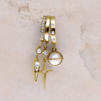 Goldene Ohrstecker mit Perlen und Glitzersteinen Drei goldene Ohrstecker mit Perlen, Glitzersteinen und Sternanhänger auf beigem Hintergrund