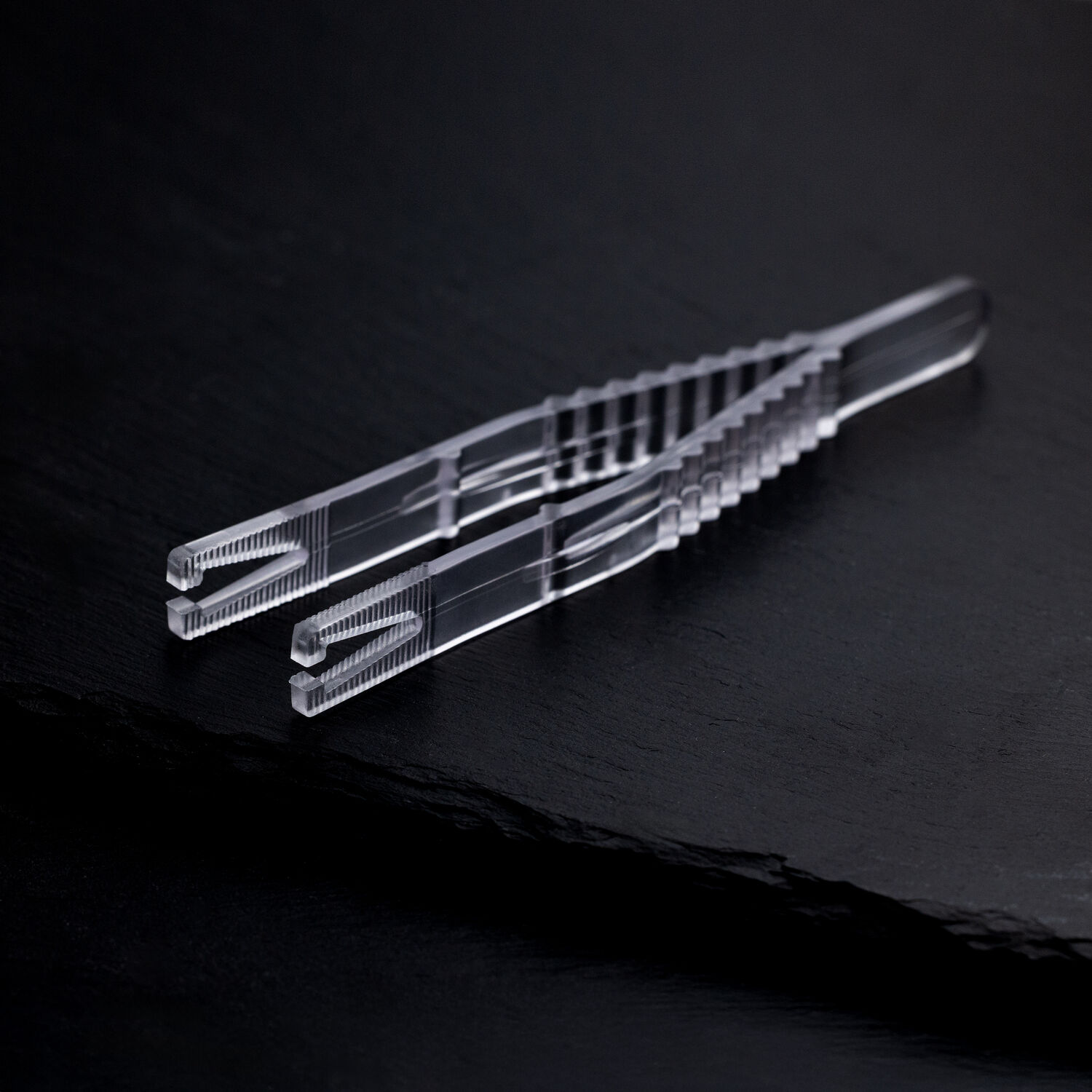 Klare sterile Triangel Piercingzange auf schwarzem Hintergrund, einzeln verpackt