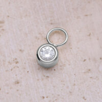 Silberner runder Kristallanhänger aus Chirurgenstahl auf beigem Hintergrund