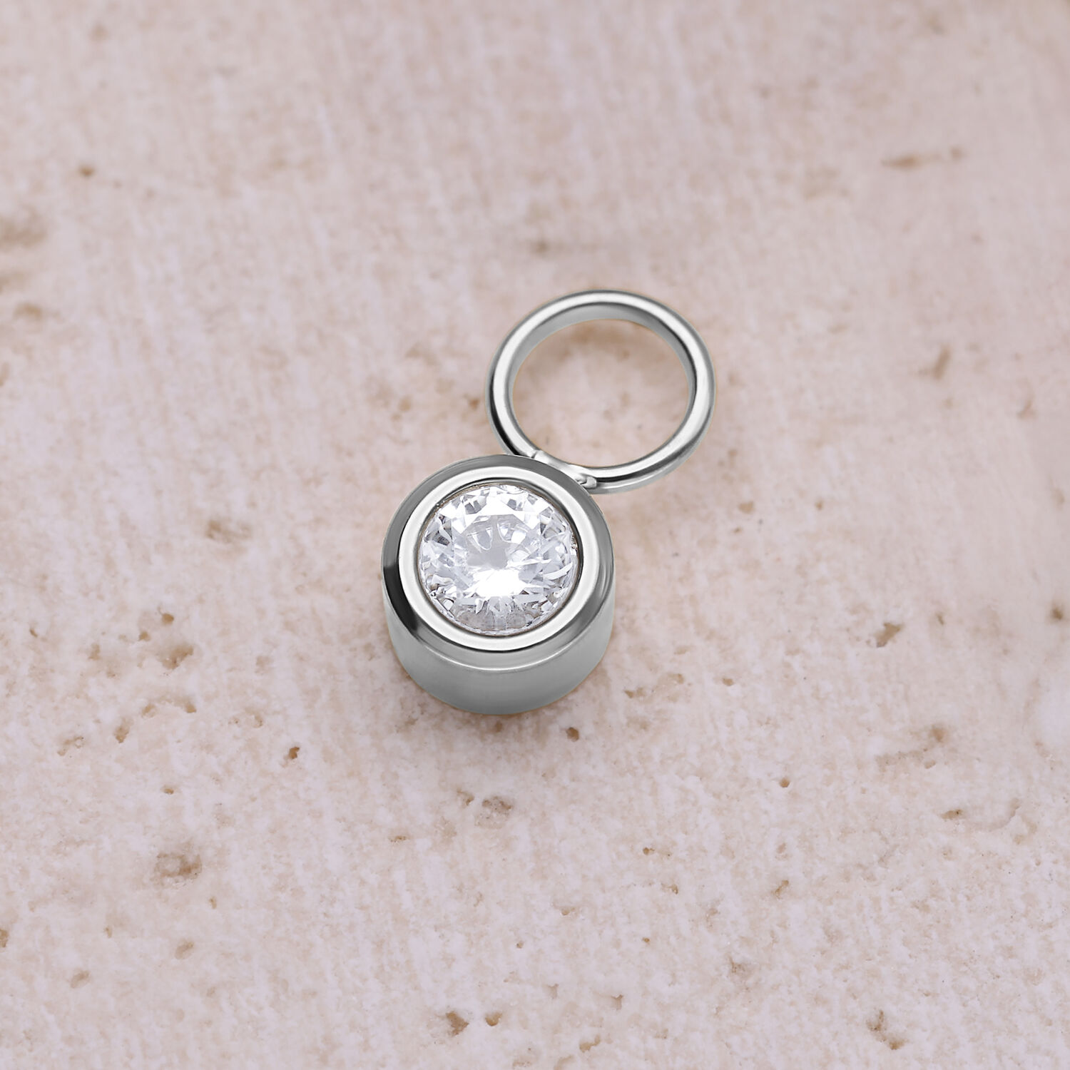 Silberner runder Kristallanhänger aus Chirurgenstahl auf beigem Hintergrund