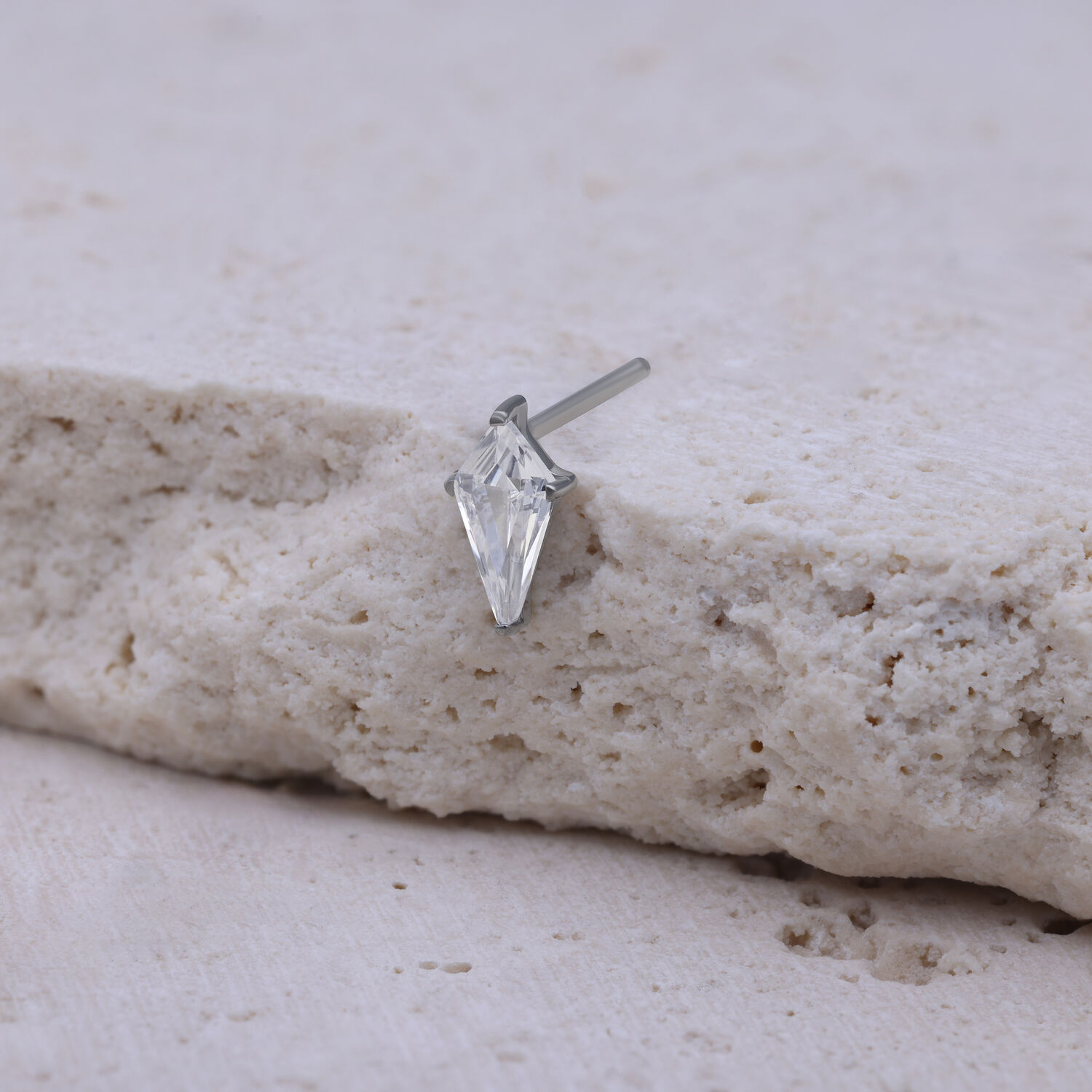 Kristallklarer Push Fit Aufsatz auf Stein Silberner Push Fit Aufsatz mit kristallklarem Stein auf beigem Hintergrund