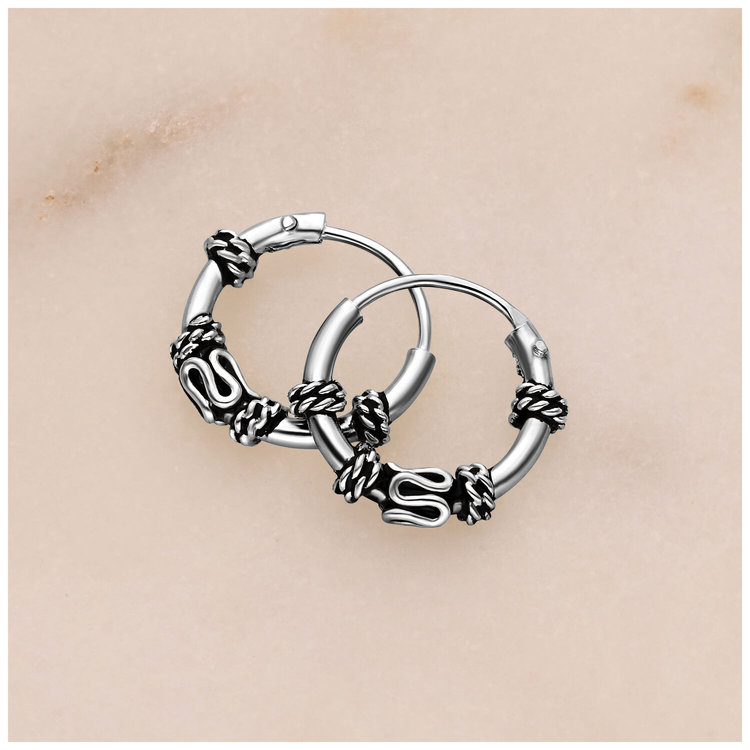 Silberne Creolen mit Knoten-Details auf hellem Hintergrund