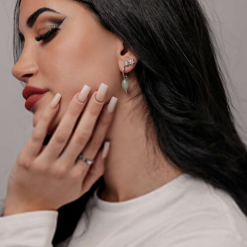 Frau mit langen schwarzen Haaren trägt grüne Aventurin Ohrringe und weißen Pullover