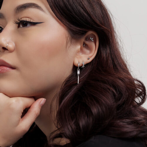 Frau mit kleinen, quadratischen Kristall-Ohrringen vor weißem Hintergrund