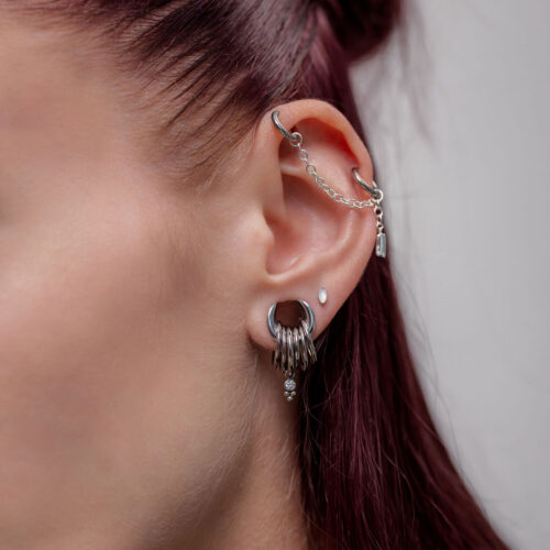 Ohr mit silberner Piercingkette und mehreren Piercings, seitliche Ansicht