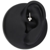 Silberner Piercing Anhänger mit drei Kristallen auf schwarzem Ohr-Modell