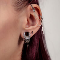 Nahaufnahme eines Ohres mit silbernen Piercingaufsätzen und Ketten