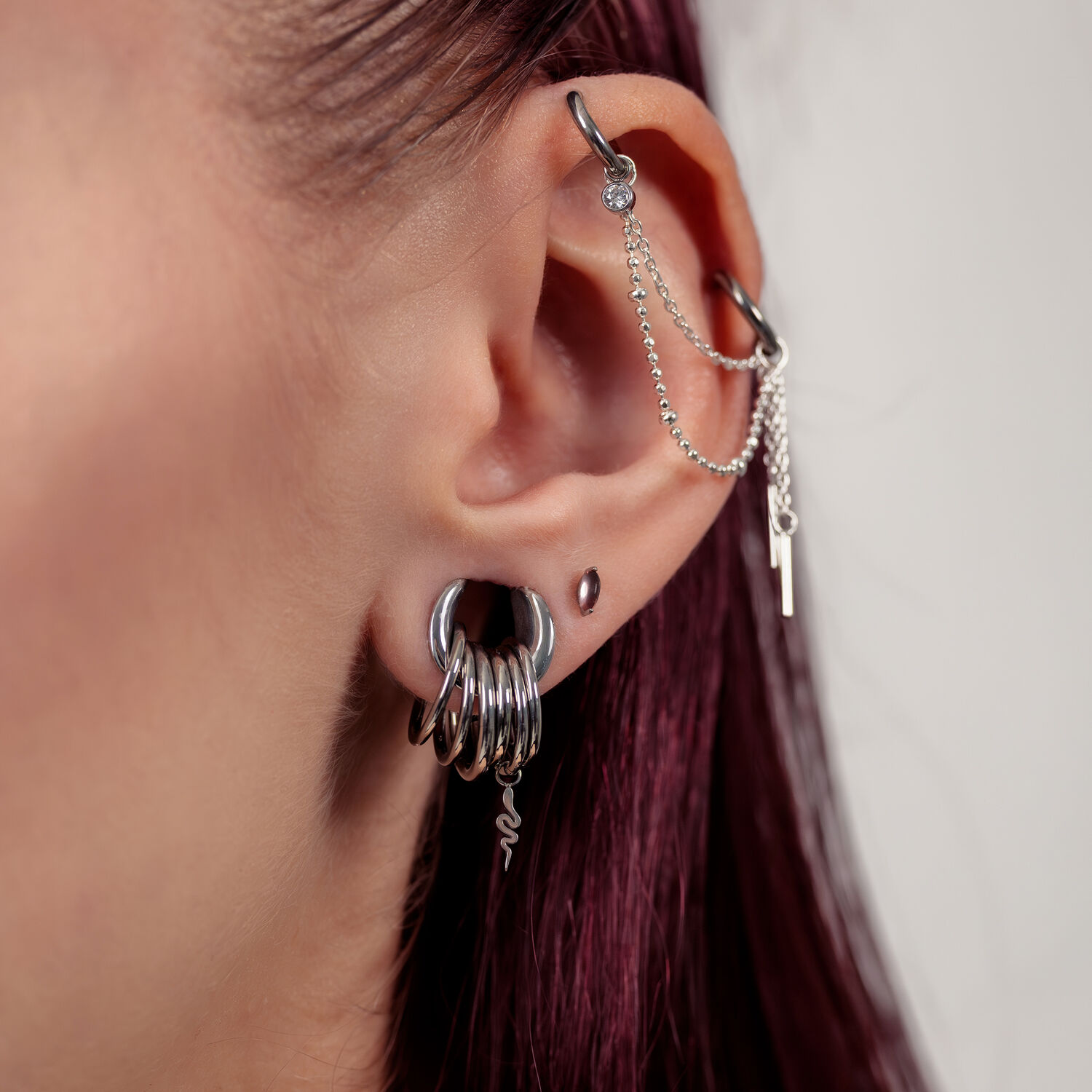 Nahaufnahme eines Ohres mit silbernen Piercingaufsätzen und Ketten