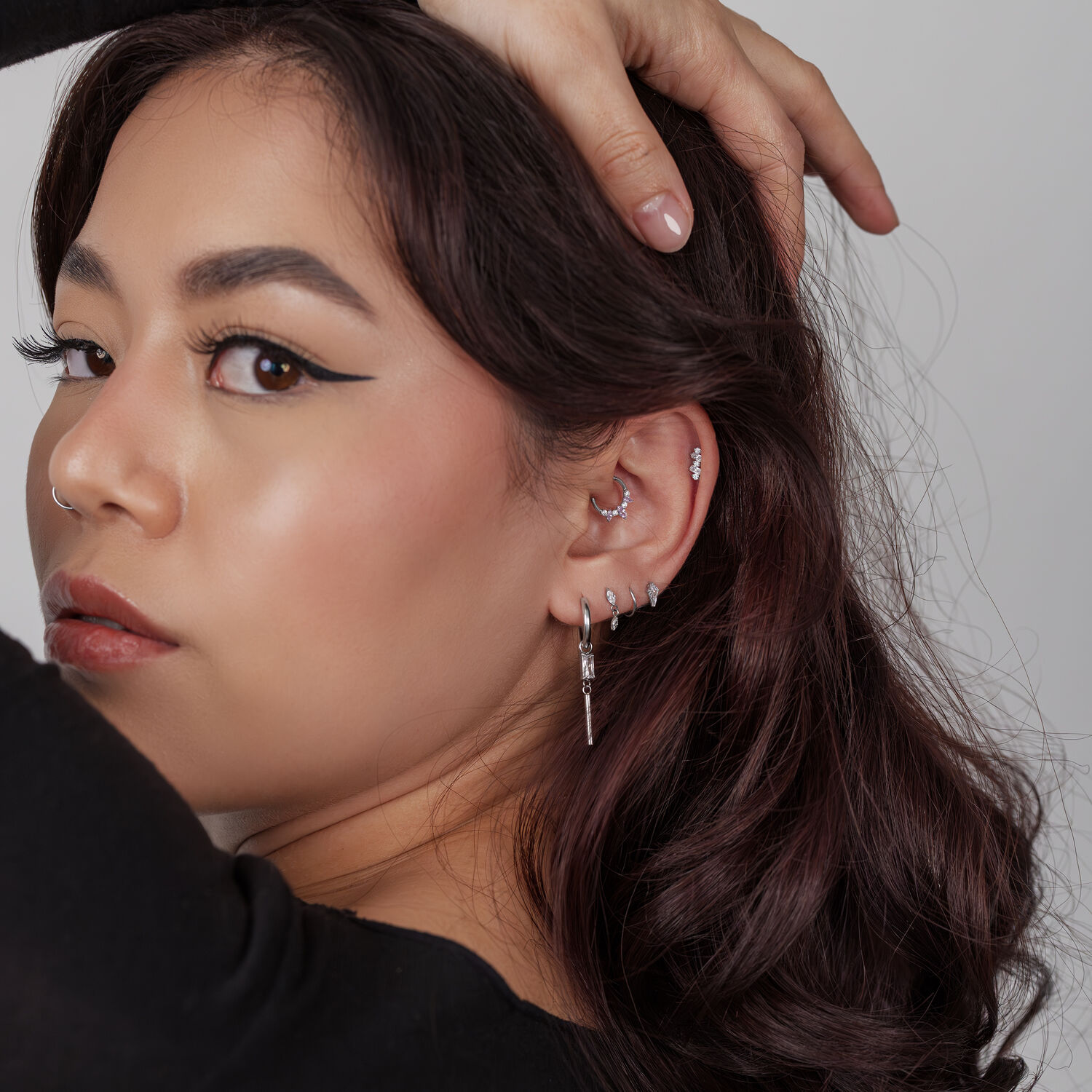 Silberner Push Fit Kristallaufsatz Frau mit mehreren silbernen Ohrpiercings, darunter ein Kristallaufsatz, vor grauem Hintergrund