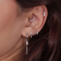 Silberne Ohrpiercings mit Kristallen Nahaufnahme eines Ohres mit mehreren silbernen Piercings, einige mit Kristallen besetzt