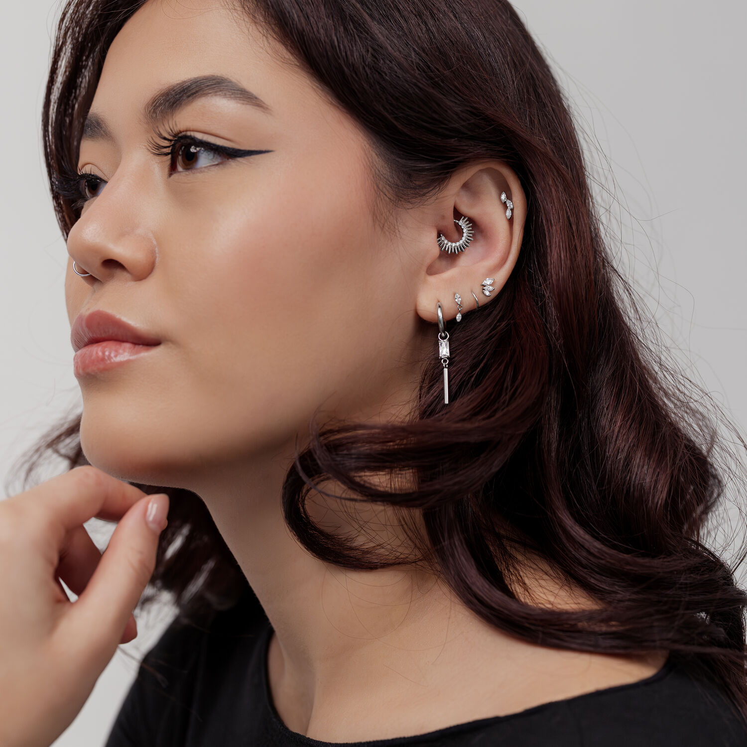 Frau mit mehreren silbernen Ohr- und Nasenpiercings, Septum Clicker in Sonnenstrahlenform